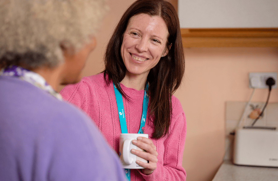 Dementia UK Nurse smiling and sharing hot drink with older woman