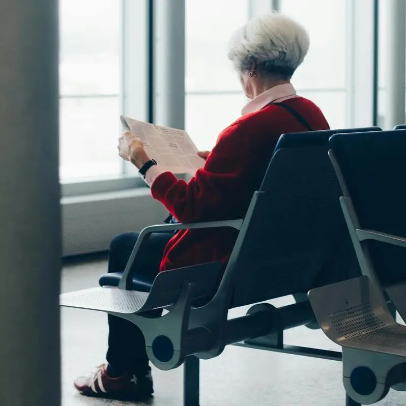 Elderly passenger reading newspaper at airport | Disabled Holiday Makers Guide